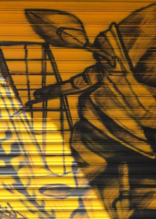 Mural con moto de carreras en cierre metálico del Barrio Blanco (Madrid), estilo urbano