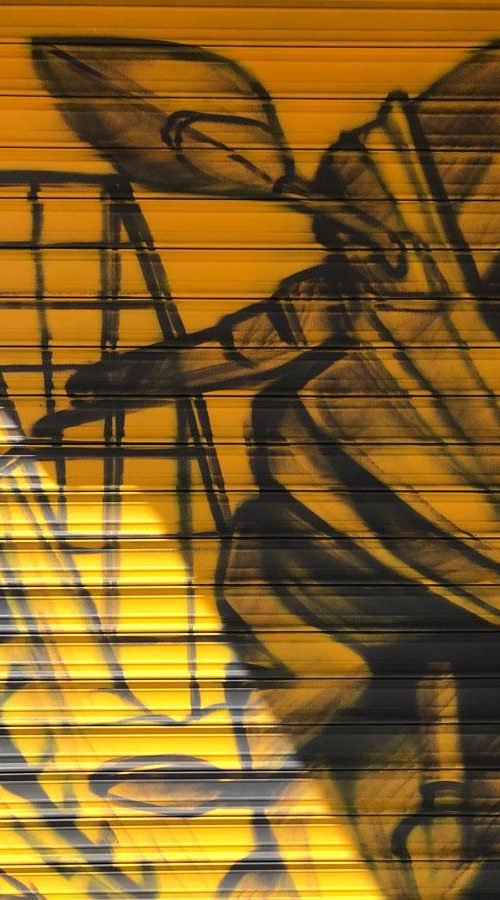 Mural con moto de carreras en cierre metálico del Barrio Blanco (Madrid), estilo urbano