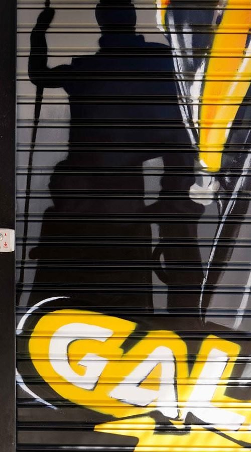 Moto deportiva amarilla y silueta urbana en mural para Gala Bravo Murillo, Madrid