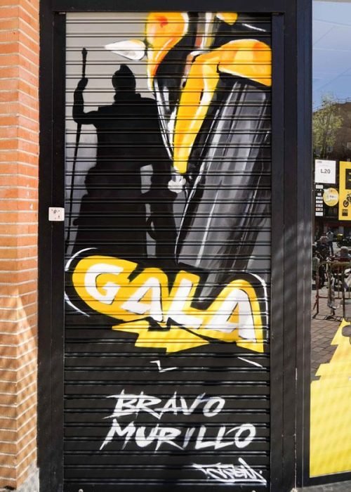 Moto deportiva amarilla y silueta urbana en mural para Gala Bravo Murillo, Madrid
