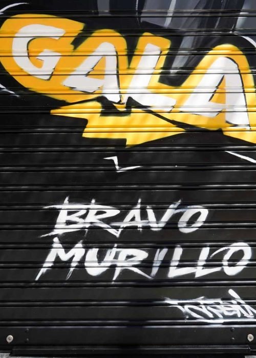 Moto deportiva amarilla y silueta urbana en mural para Gala Bravo Murillo, Madrid