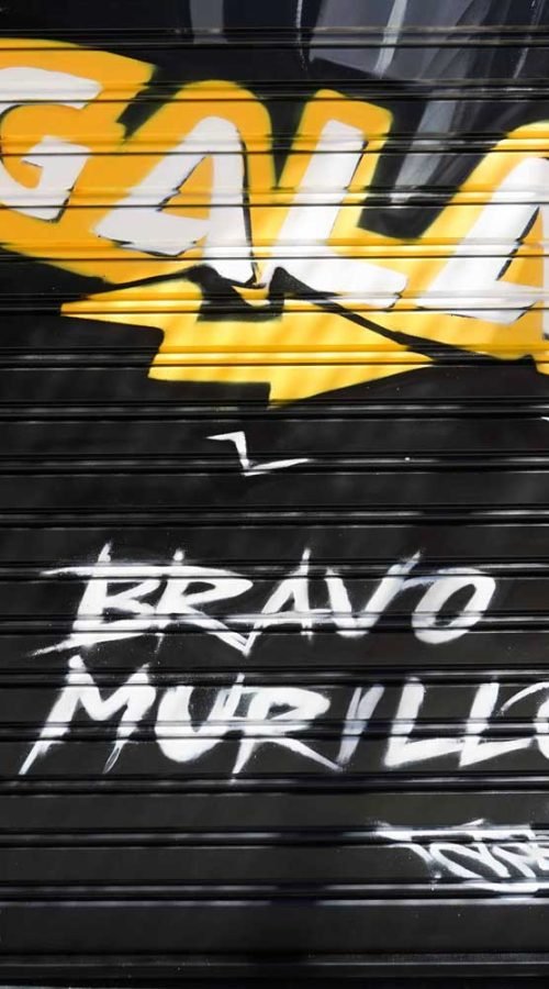 Moto deportiva amarilla y silueta urbana en mural para Gala Bravo Murillo, Madrid