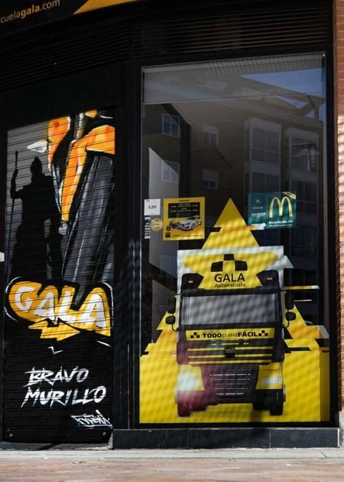 Moto deportiva amarilla y silueta urbana en mural para Gala Bravo Murillo, Madrid