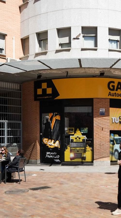 Moto deportiva amarilla y silueta urbana en mural para Gala Bravo Murillo, Madrid