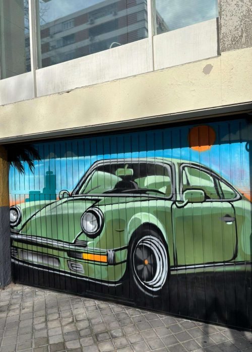 Detalle de mural graffiti en puerta de garaje con coche clásico verde y fondo azul