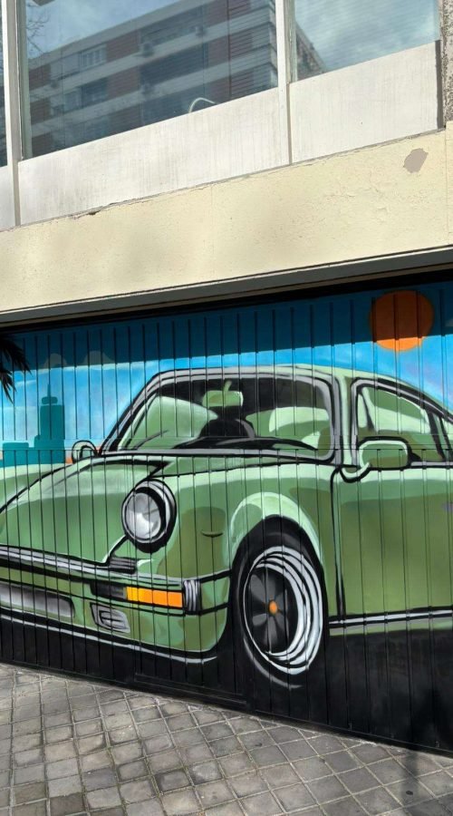 Detalle de mural graffiti en puerta de garaje con coche clásico verde y fondo azul