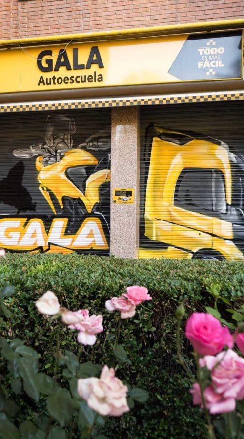 Cierre pintado de Autoescuela Gala con camión y moto en estilo urbano