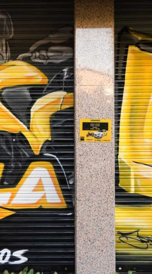 Cierre pintado de Autoescuela Gala con camión y moto en estilo urbano