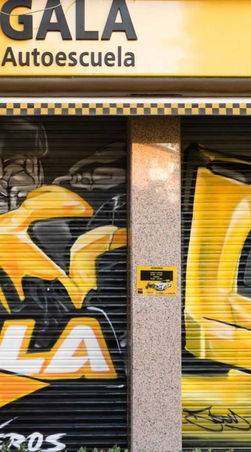 Cierre pintado de Autoescuela Gala con camión y moto en estilo urbano