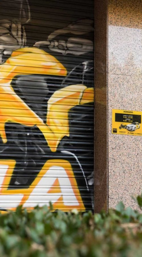 Cierre pintado de Autoescuela Gala con camión y moto en estilo urbano