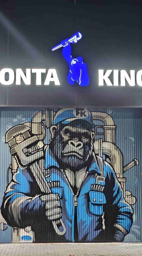 Mural en fachada de negocio Fontaking con gorila fontanero y llave inglesa sobre puerta industrial