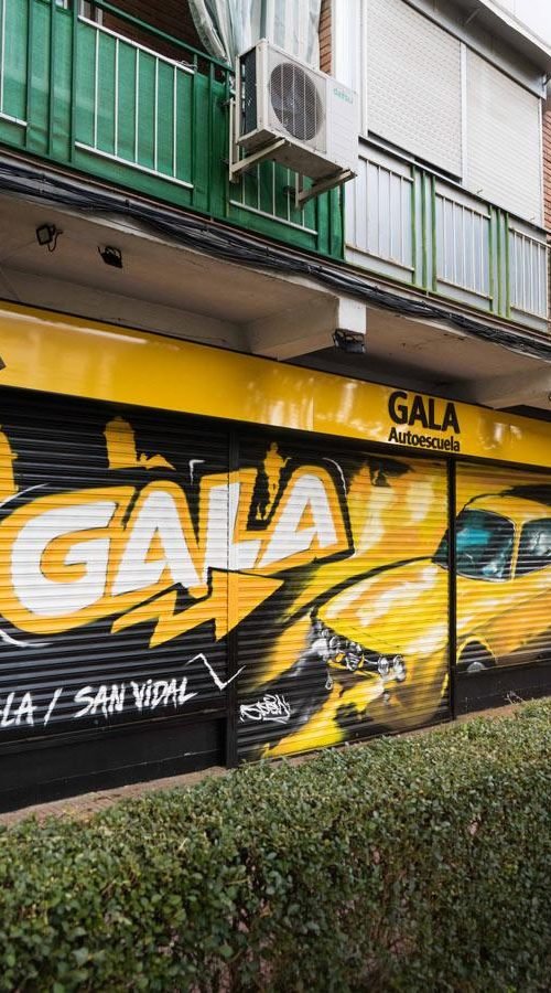 Cierre con mural de Rolls-Royce amarillo para Autoescuela Gala en estilo graffiti