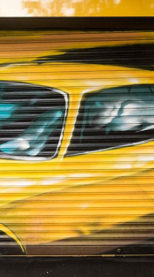 Cierre con mural de Rolls-Royce amarillo para Autoescuela Gala en estilo graffiti