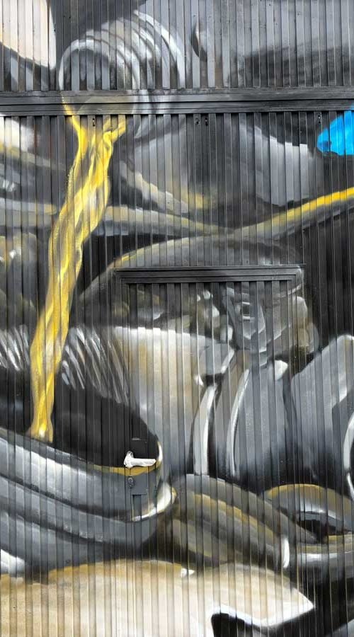 Graffiti de mecánica y engranajes en fachada de Euromaster Julián Camarillo