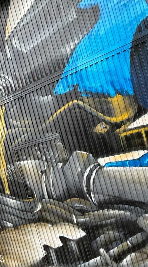 Graffiti de mecánica y engranajes en fachada de Euromaster Julián Camarillo