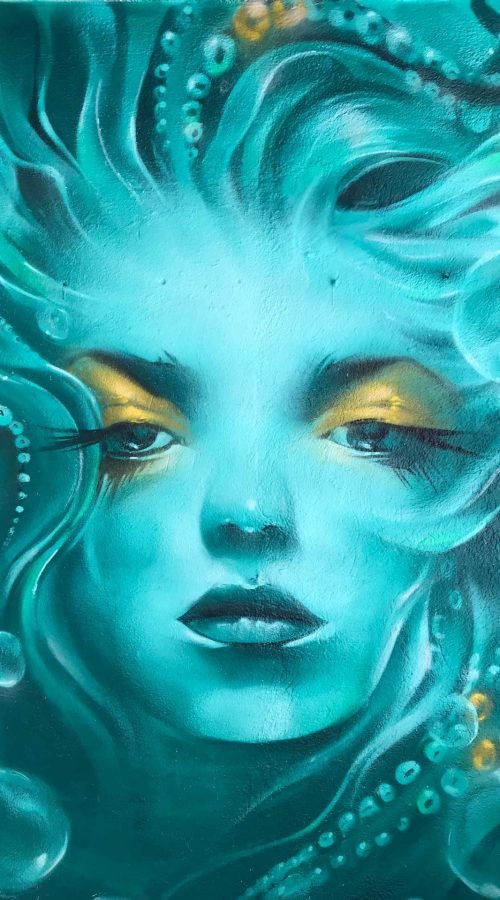 Mural urbano con rostro femenino turquesa en terraza interior