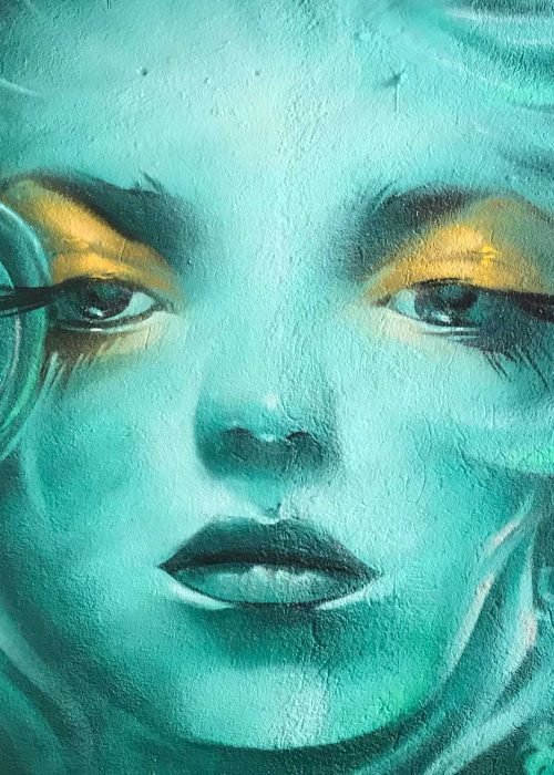 Mural urbano con rostro femenino turquesa en terraza interior