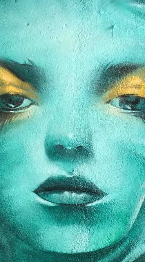 Mural urbano con rostro femenino turquesa en terraza interior