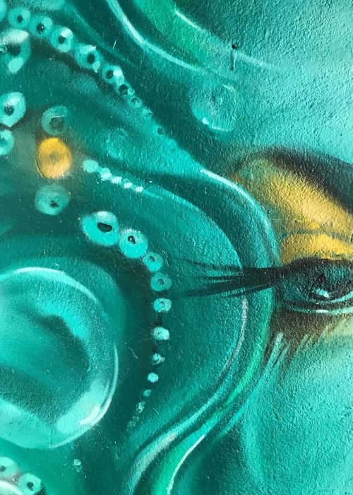 Mural urbano con rostro femenino turquesa en terraza interior