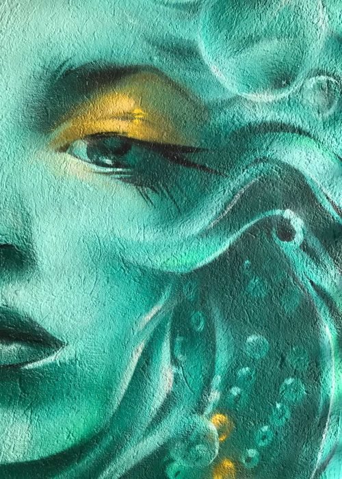 Mural urbano con rostro femenino turquesa en terraza interior