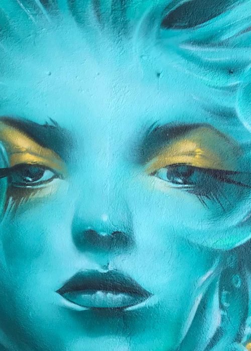 Mural urbano con rostro femenino turquesa en terraza interior