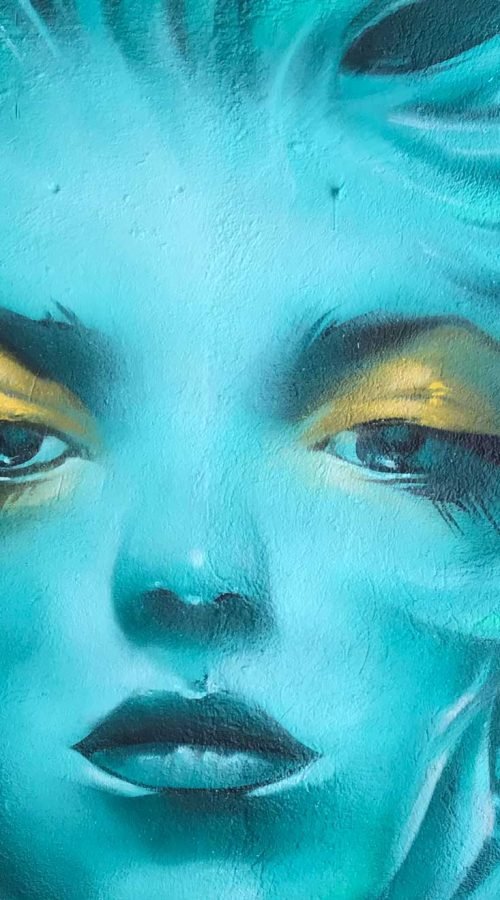 Mural urbano con rostro femenino turquesa en terraza interior