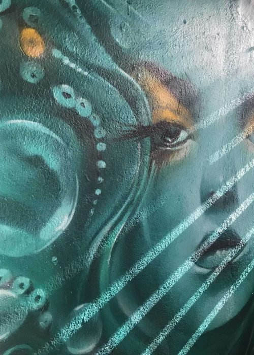 Mural urbano con rostro femenino turquesa en terraza interior