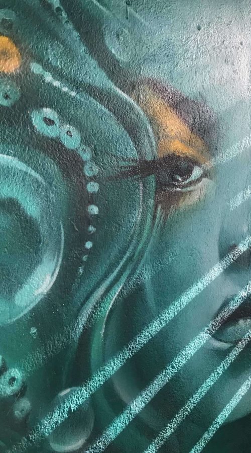 Mural urbano con rostro femenino turquesa en terraza interior