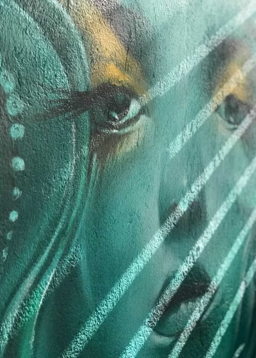 Mural urbano con rostro femenino turquesa en terraza interior
