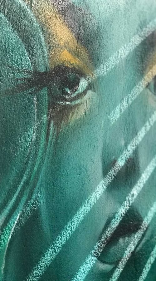 Mural urbano con rostro femenino turquesa en terraza interior
