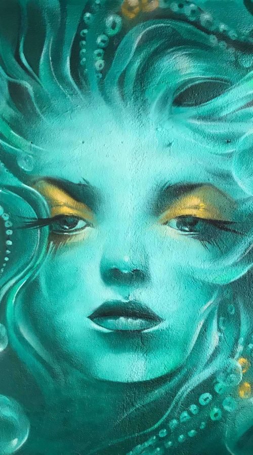 Mural urbano con rostro femenino turquesa en terraza interior