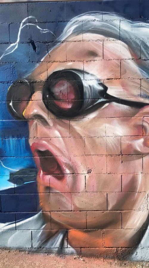 Mural graffiti de Marty McFly y el Delorean de Back to the Future con colores vivos y estilo ochentero