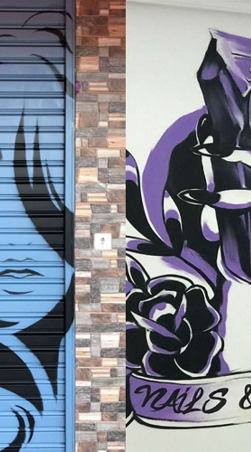 Murales urbano en salón Nails & Barber con silueta femenina y mano tatuada en tonos púrpura