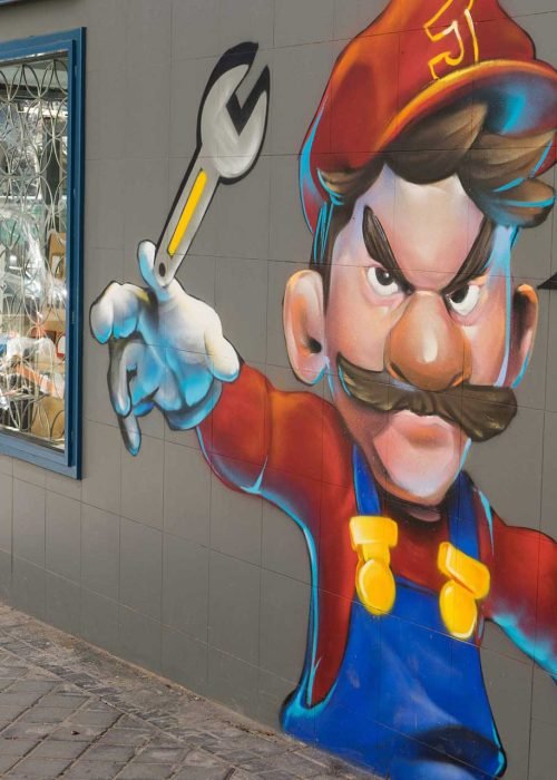 Mural para fontanería con personaje tipo Mario y herramientas, arte urbano comercial