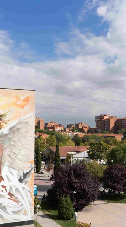 Mural institucional con ángel y lettering graffiti en fachada pública de Madrid