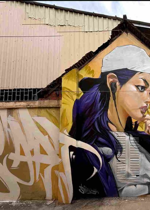 Mural graffiti en fachada de Camboya, retrato femenino con gorra para S’art Urban Art Festival.