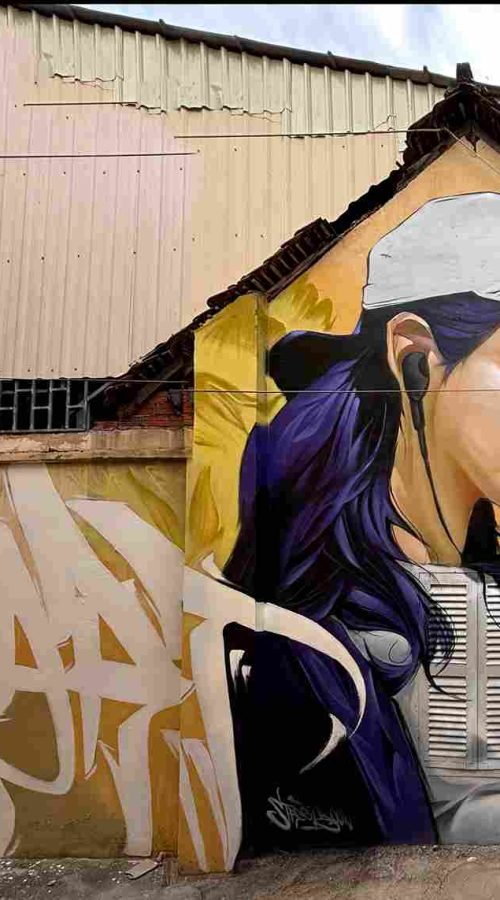 Mural graffiti en fachada de Camboya, retrato femenino con gorra para S’art Urban Art Festival.