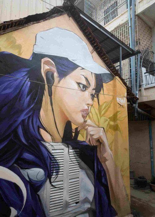 Mural graffiti en fachada de Camboya, retrato femenino con gorra para S’art Urban Art Festival.