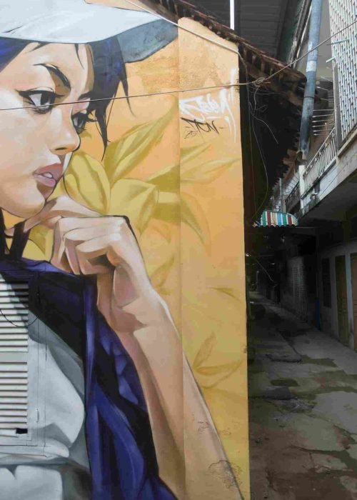 Mural graffiti en fachada de Camboya, retrato femenino con gorra para S’art Urban Art Festival.