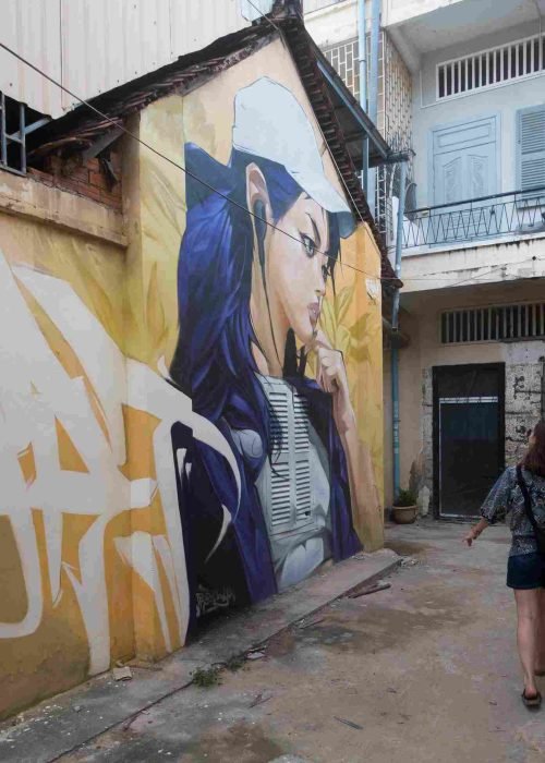 Mural graffiti en fachada de Camboya, retrato femenino con gorra para S’art Urban Art Festival.