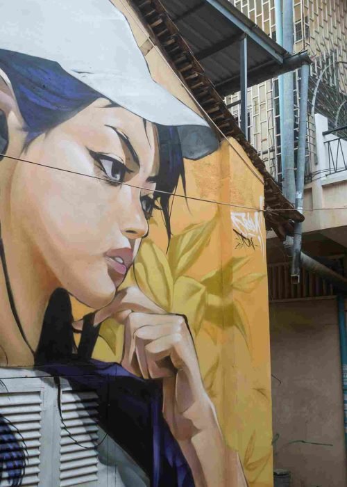 Mural graffiti en fachada de Camboya, retrato femenino con gorra para S’art Urban Art Festival.