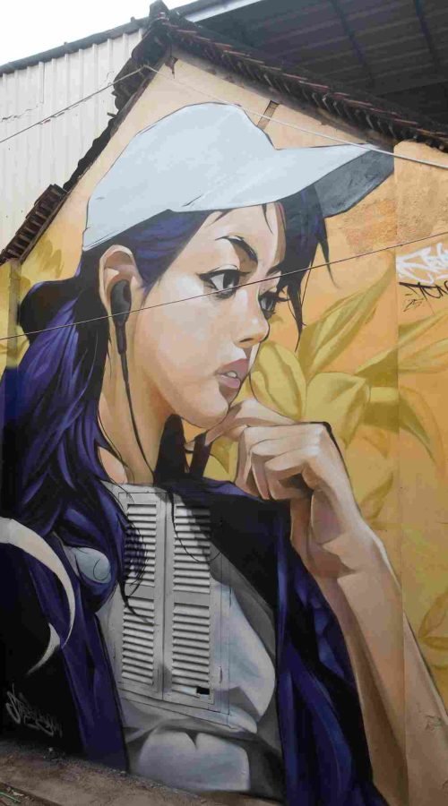 Mural graffiti en fachada de Camboya, retrato femenino con gorra para S’art Urban Art Festival.