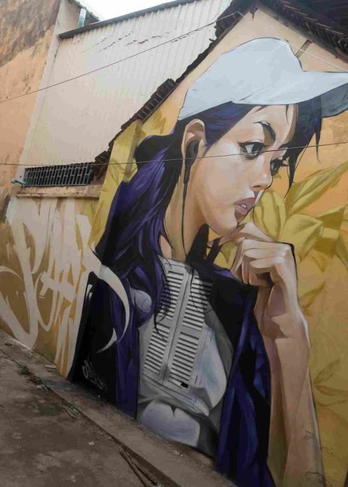 Mural graffiti en fachada de Camboya, retrato femenino con gorra para S’art Urban Art Festival.