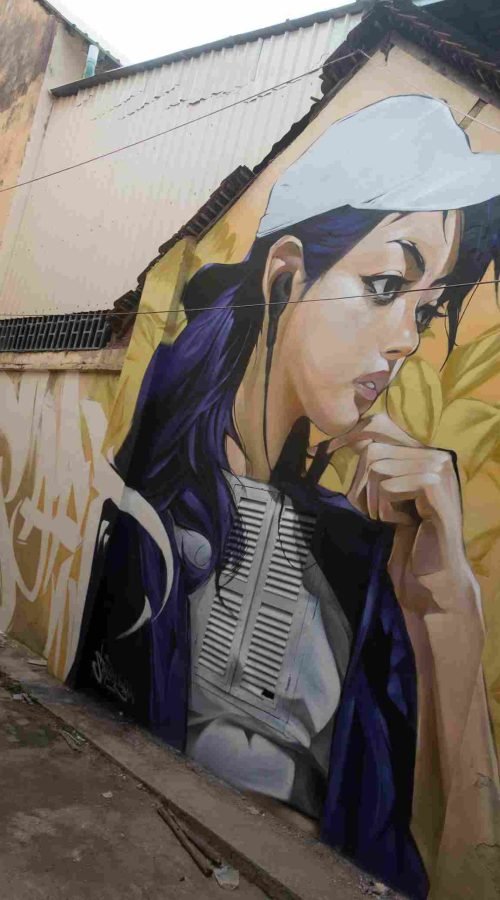 Mural graffiti en fachada de Camboya, retrato femenino con gorra para S’art Urban Art Festival.