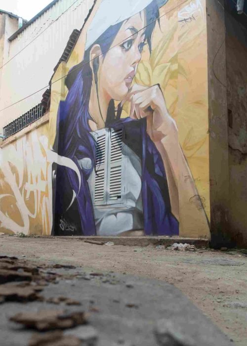 Mural graffiti en fachada de Camboya, retrato femenino con gorra para S’art Urban Art Festival.