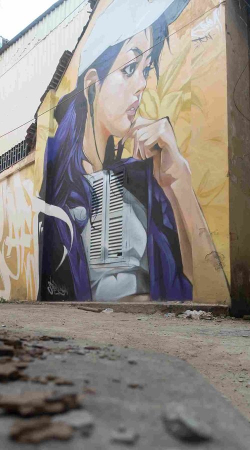 Mural graffiti en fachada de Camboya, retrato femenino con gorra para S’art Urban Art Festival.