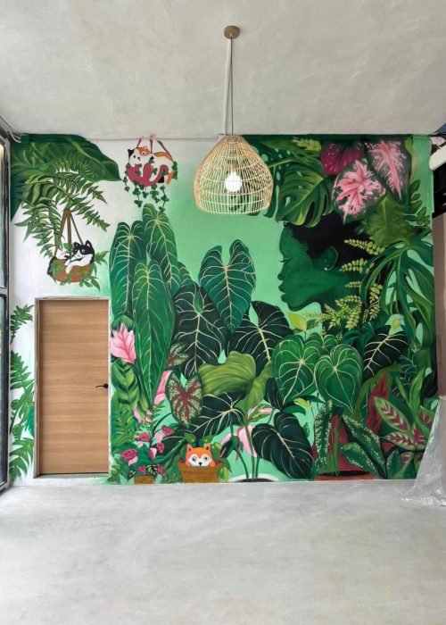 Mural de hojas tropicales en Torrelavega con composición vista a través de cerramiento negro interior