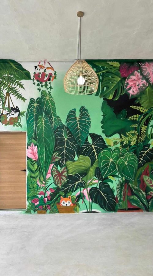 Mural de hojas tropicales en Torrelavega con composición vista a través de cerramiento negro interior