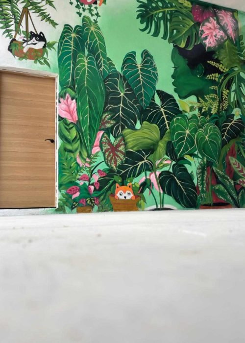 Detalle de mural botánico en Cantabria con grandes hojas verdes pintadas sobre pared interior