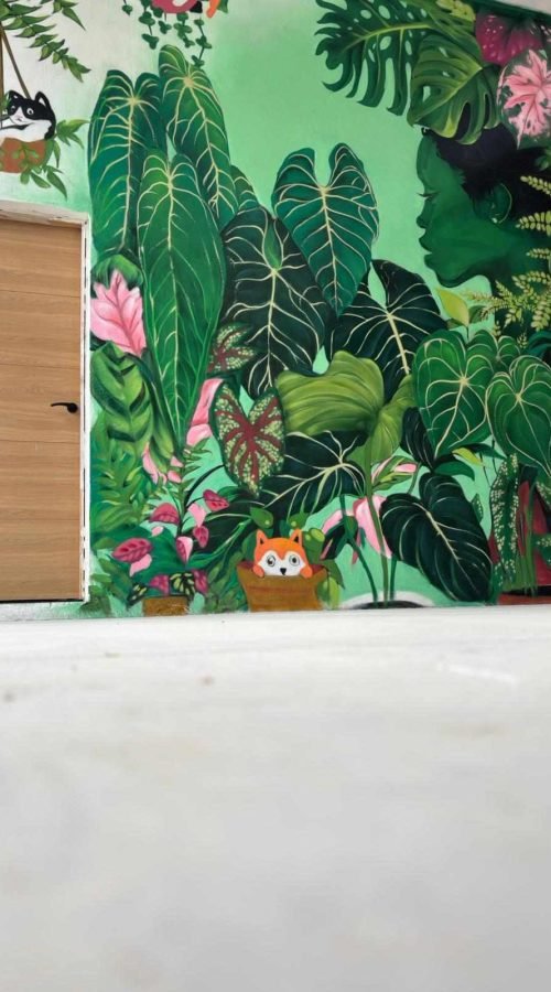 Detalle de mural botánico en Cantabria con grandes hojas verdes pintadas sobre pared interior